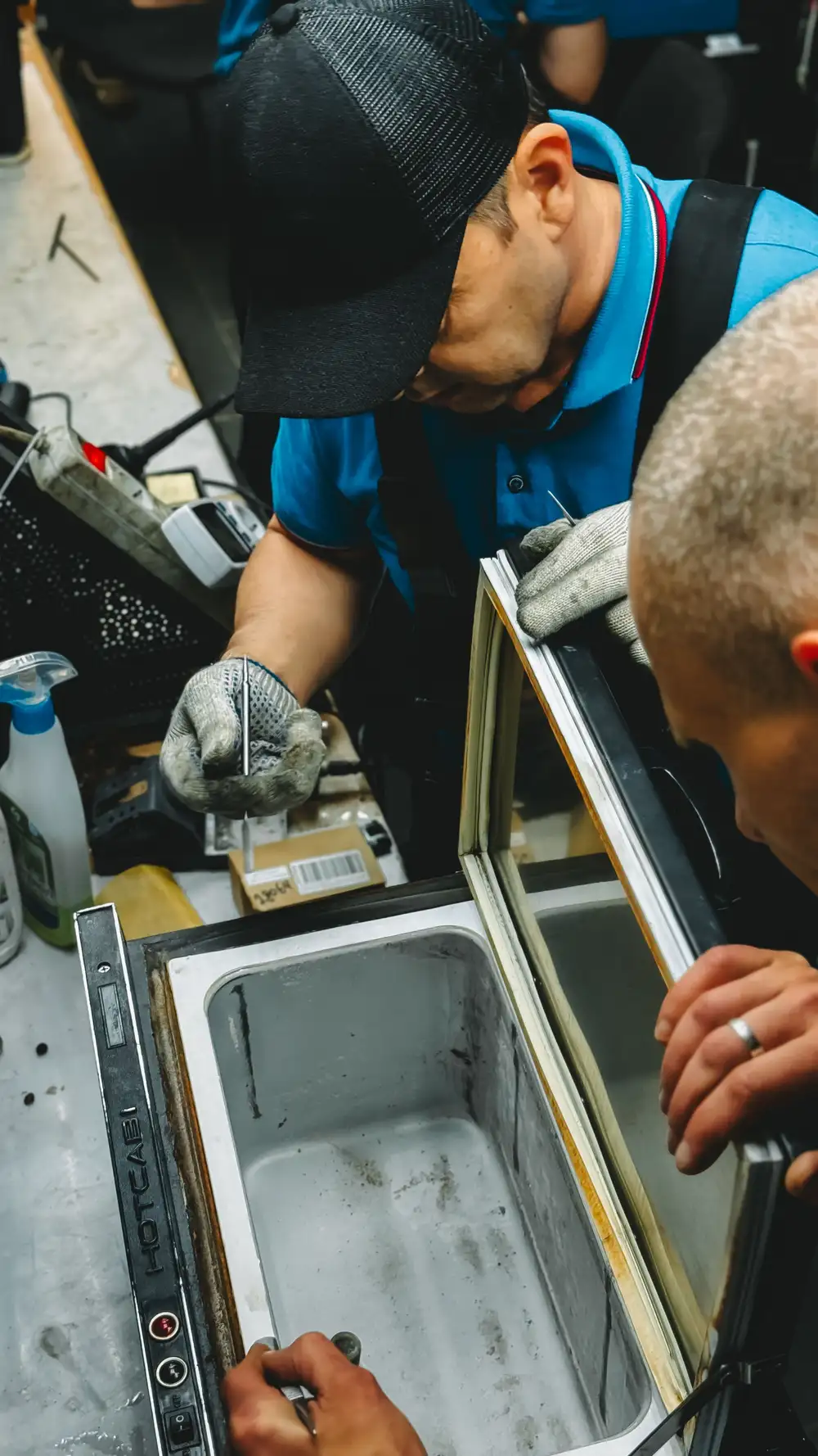 Refrigerator repair technician diagnosing a kitchen refrigerator in Portland, OR